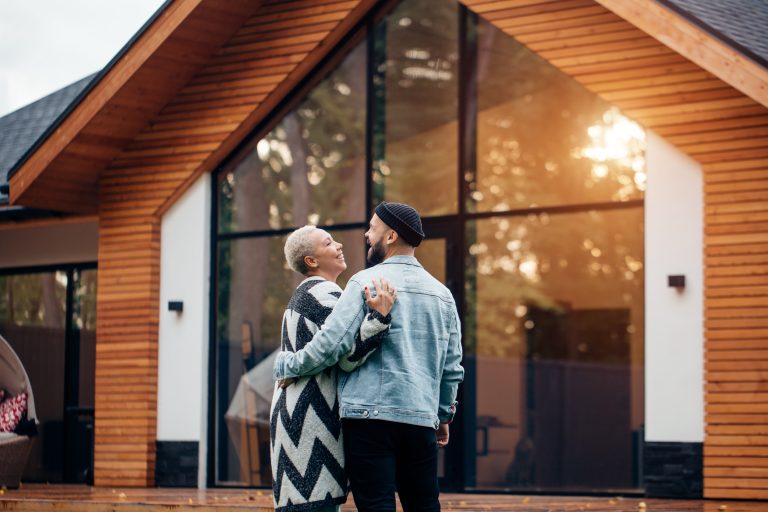 Happy young married couple look at their house